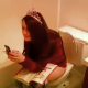 A girl wearing a pageant crown is pooping and smoking on a toilet while her friend video records the event. The video is not very clear, but we get to see her finished product.